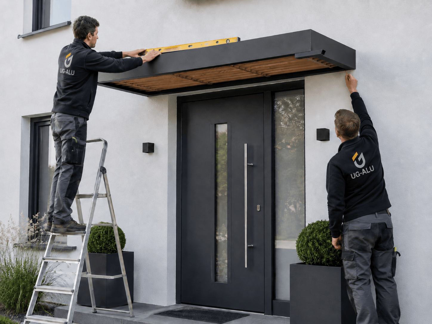 UG-ALU-Monteure richten das Scobalit Haustürvordach Holzminden an der Hauswand aus